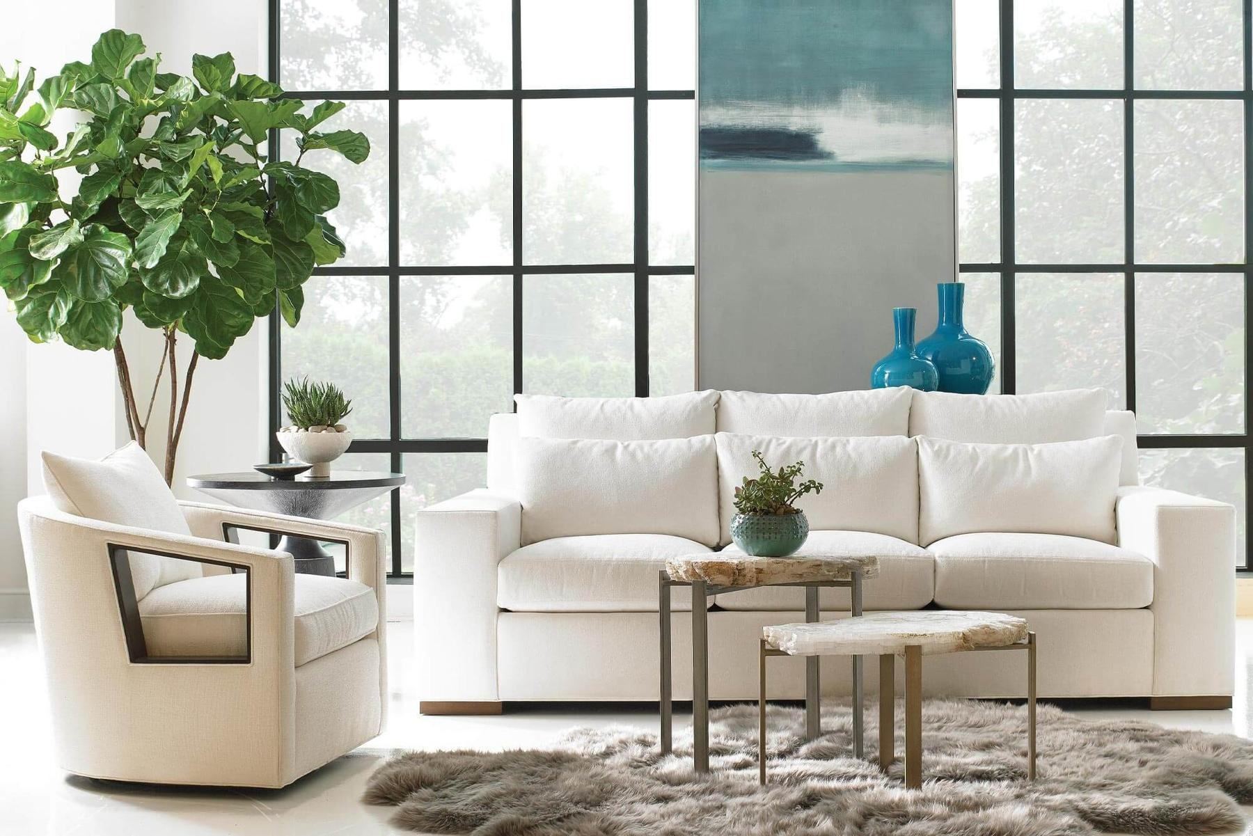 Bright white living room with a deep sofa, swivel chair and brass nesting tables