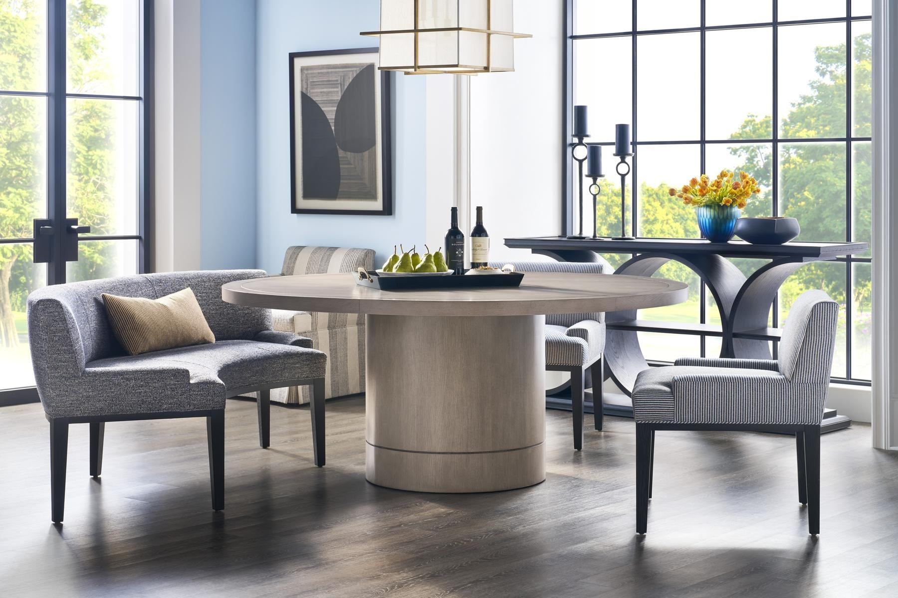 Dining room with a round pedestal table, upholstered banquette and linen chairs