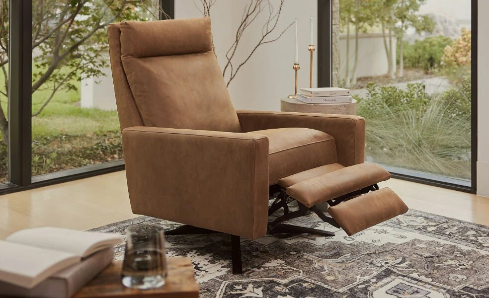 Cognac leather recliner with its footrest extended beside a window